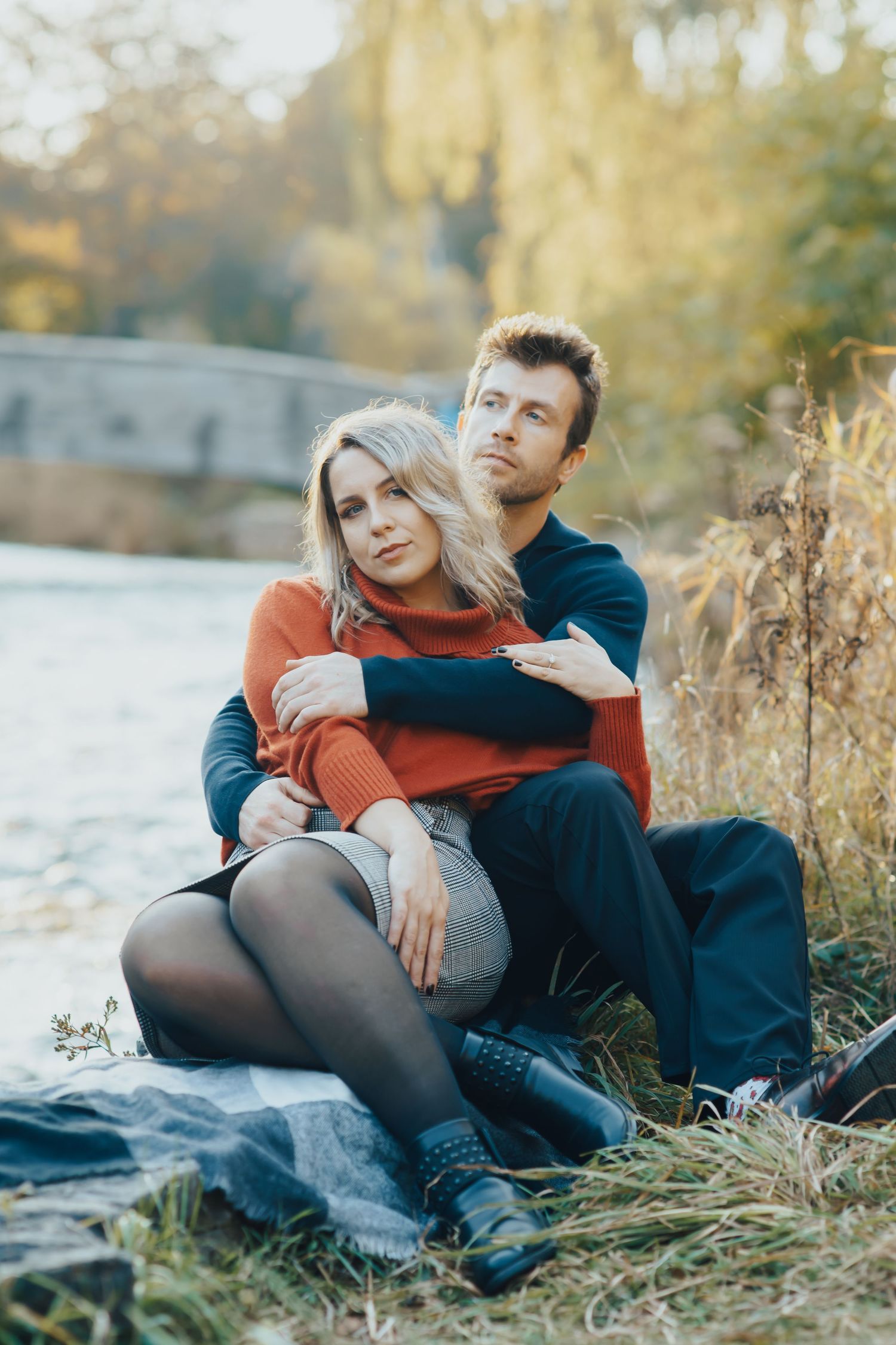 Image of woman and man sitting on rock together by water.