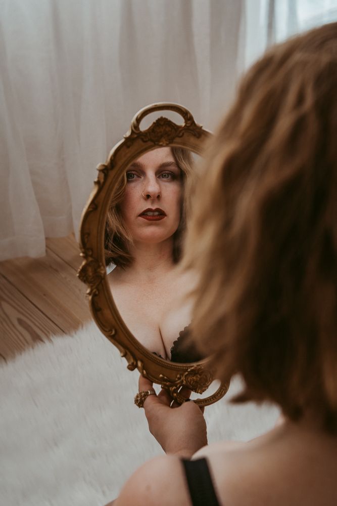 Vintage-style mirror reflection showing dramatic makeup and an ornate antique frame.