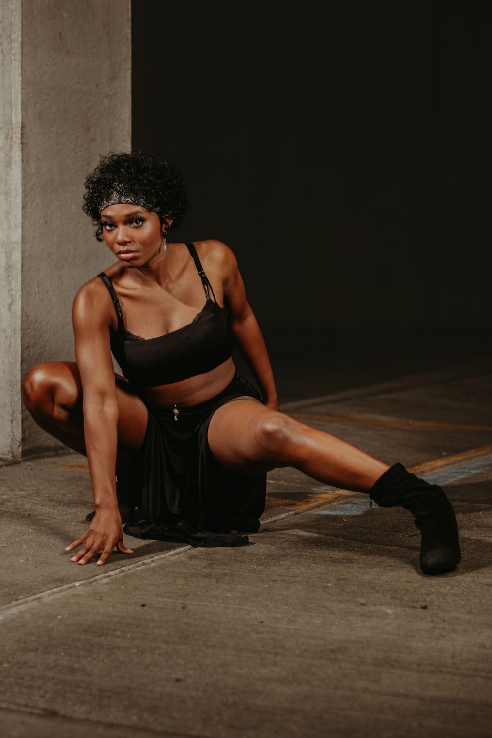 Athletic model in black activewear demonstrates flexibility in moody industrial setting.