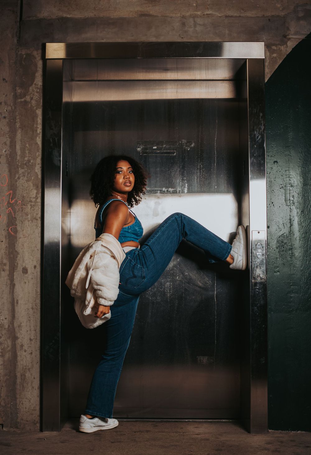 Dynamic pose against industrial concrete backdrop in urban setting.