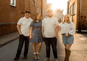 Four people pose together on a brick-lined street during golden hour.