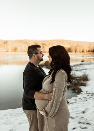 Intimate winter maternity photo by frozen lake at sunset.