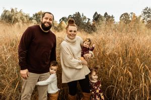 A joyful family portrait taken in tall autumn grass during golden hour.