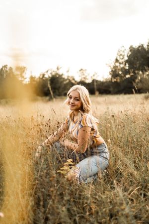 A candid portrait in a sun-drenched field of tall grass during golden hour.