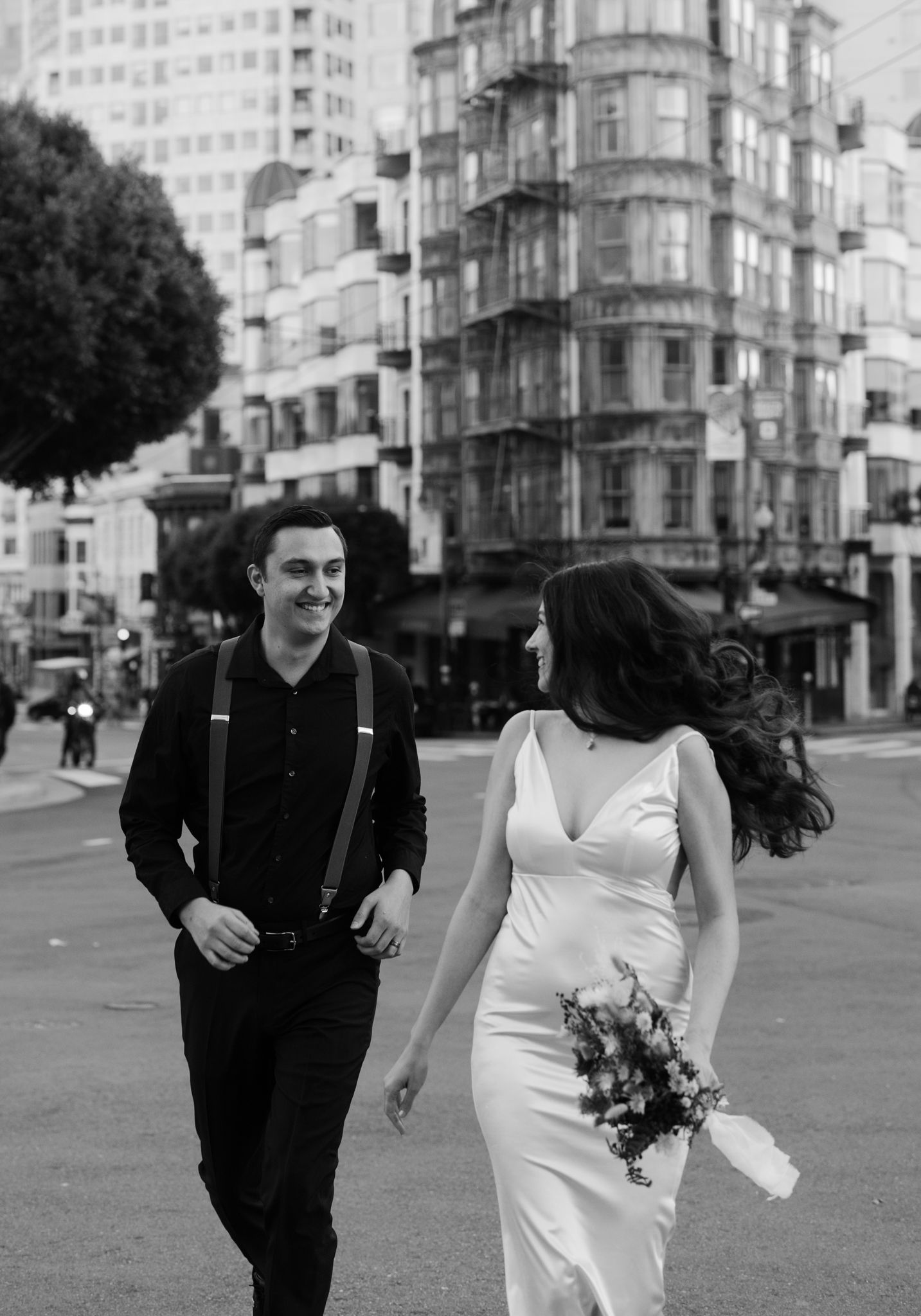 San Francisco Elopement Photographer - groom is chasing bride through a city street while she holds a bouquet