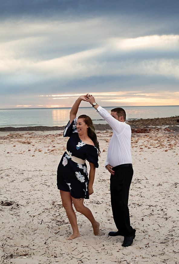 Krystal being spun by her husband on the beach with the sun setting in the background