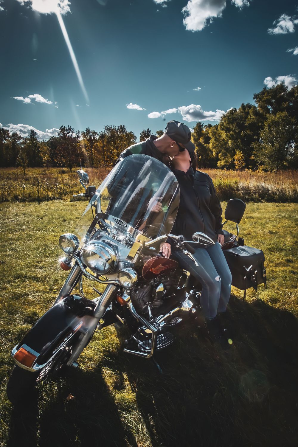 Classic motorcycle parked in an autumn field under bright blue skies and sunlight.