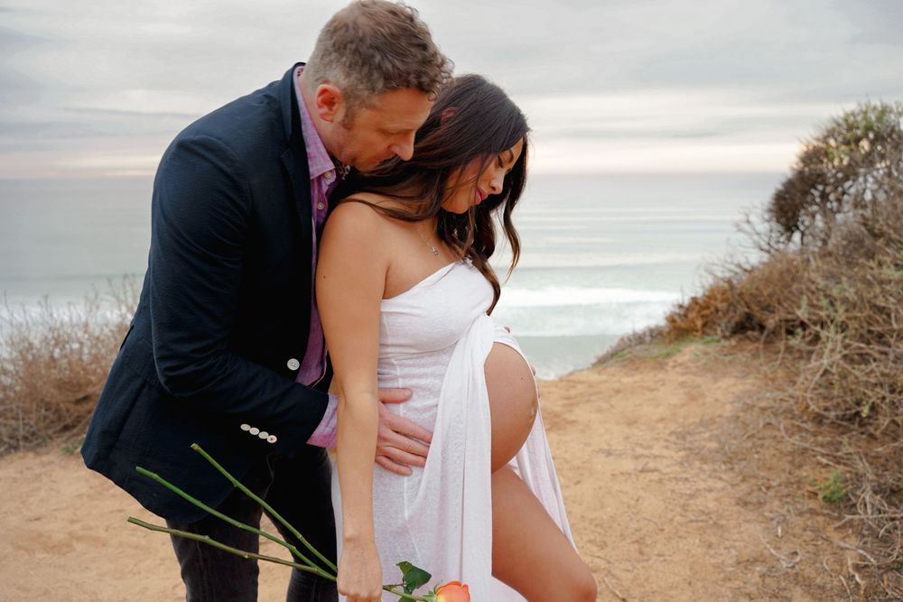 Romantic maternity photo session on coastal path during sunset.