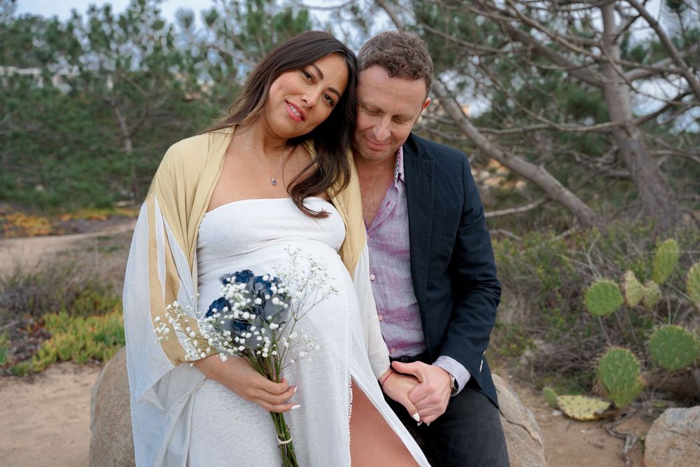 Couple shares intimate moment during outdoor maternity photoshoot.