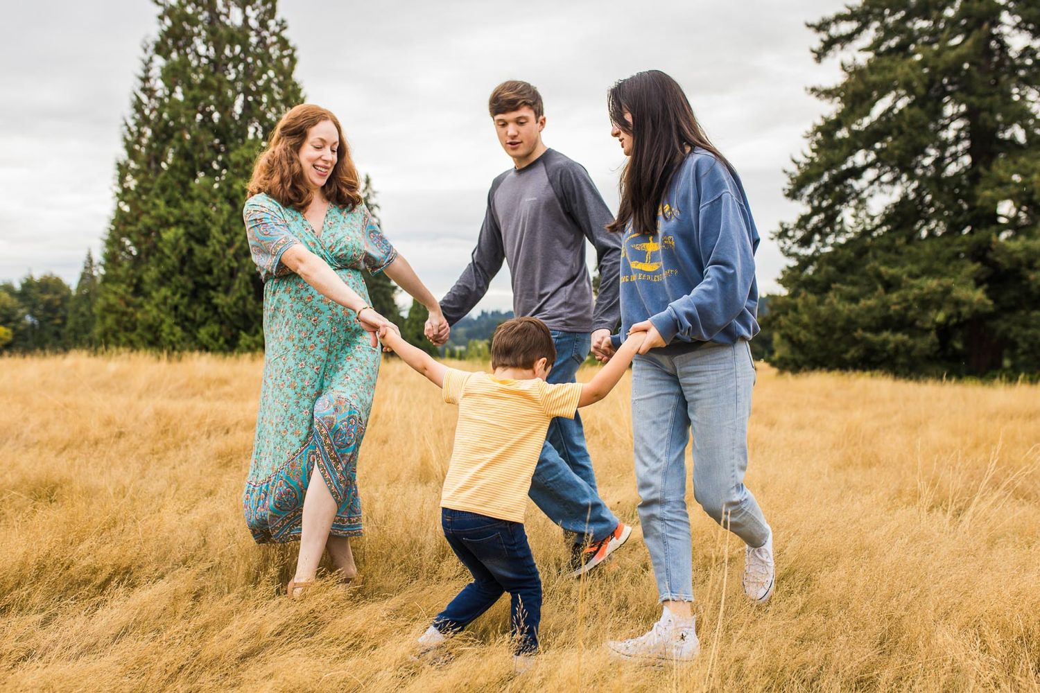 Bellevue family photographer capturing family playing ring around the rosy in a field