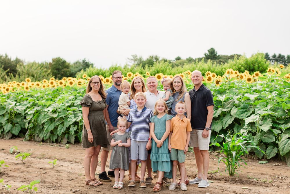 Multi-generational group poses together in front of a vibrant sunflower field.