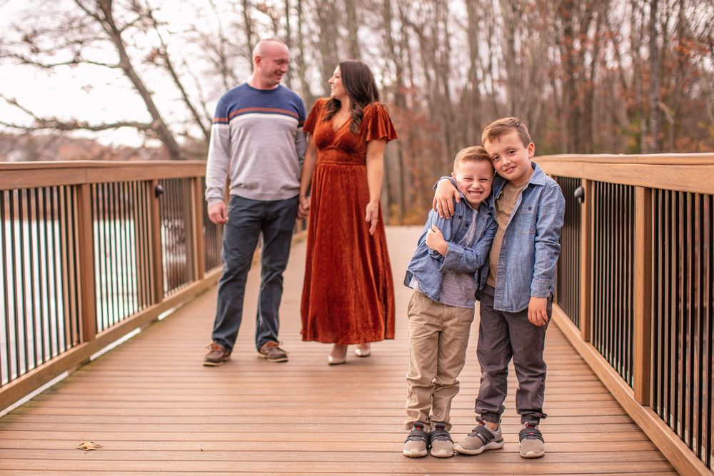 Family enjoying time together on a wooden bridge walkway in an autumn forest setting.
