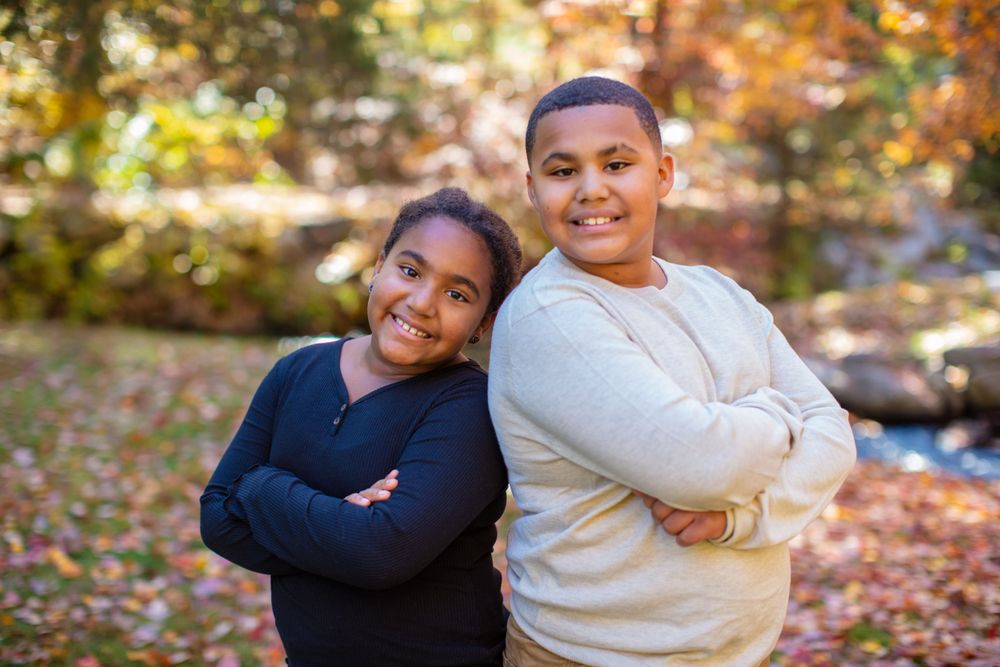 A playful outdoor photoshoot against an autumn backdrop with fallen leaves.