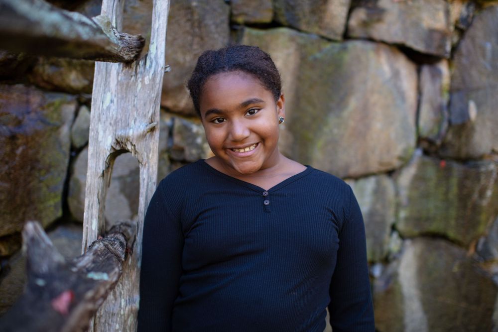 Casual portraits taken against a rustic stone wall background outdoors.