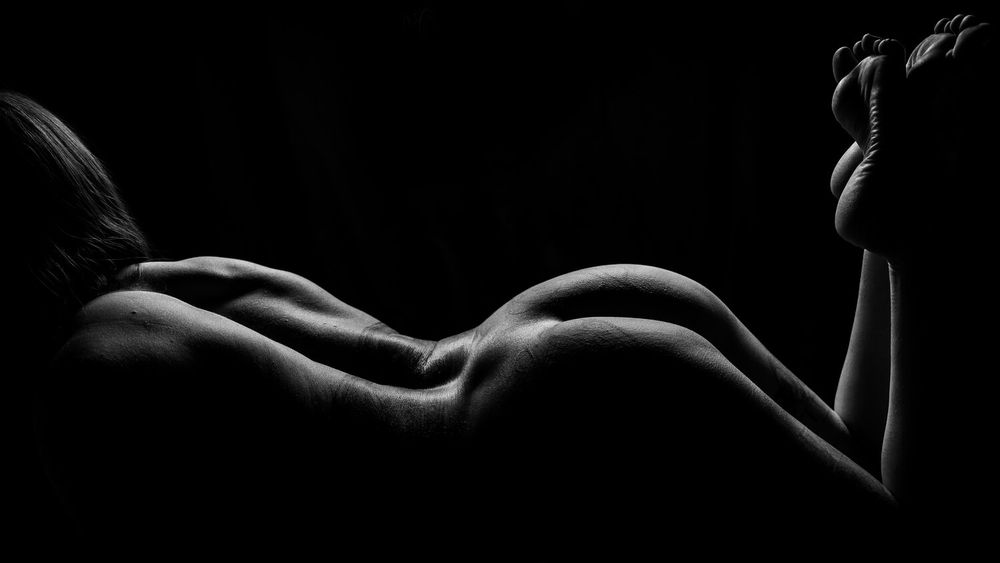 Elegant black and white silhouette showing graceful curves and contours against dark backdrop.