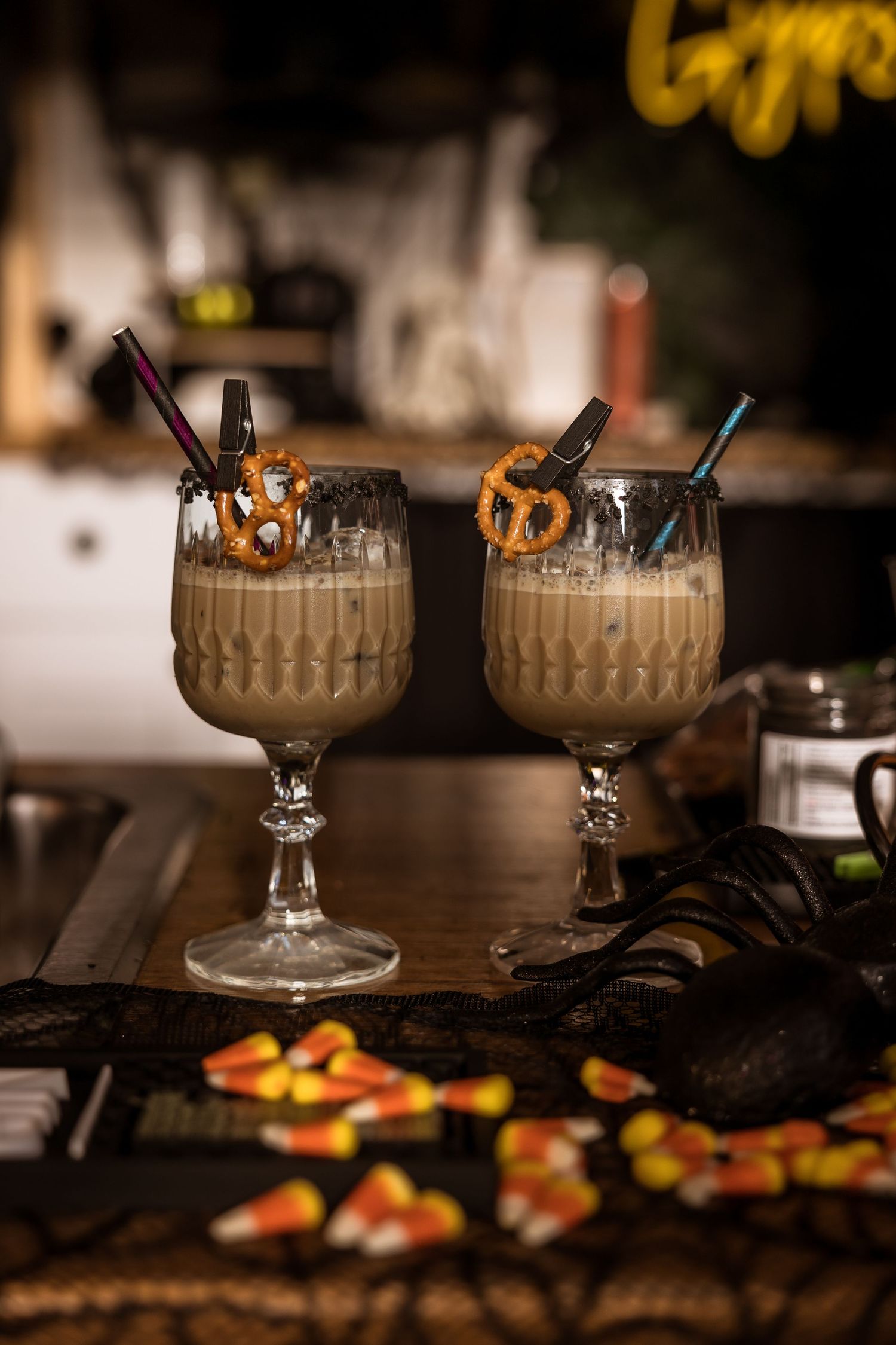 Halloween cocktails garnished with pretzels and candy corn served in vintage glass goblets.