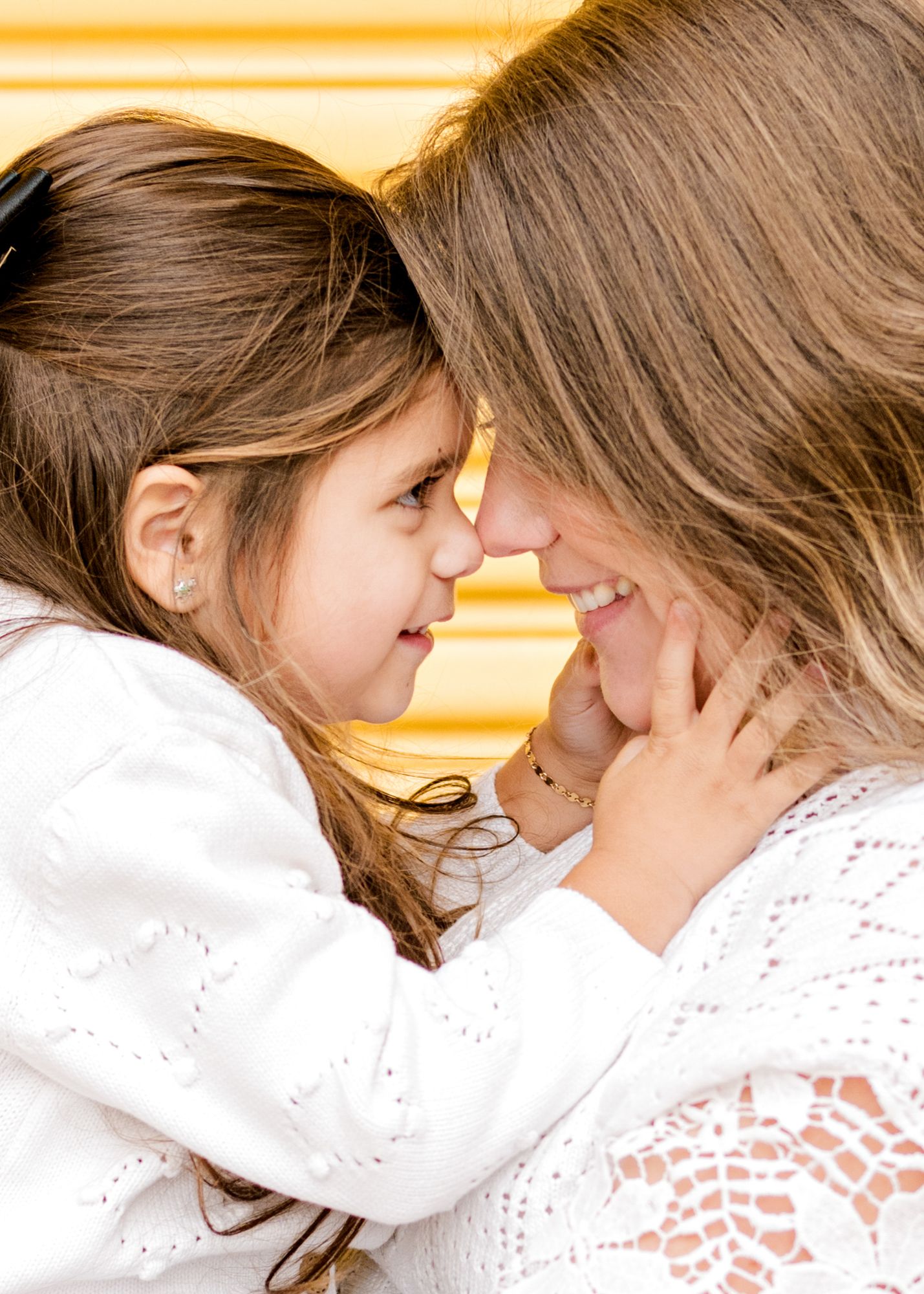 Intimate close-up portrait against yellow background showing tender affectionate moment.