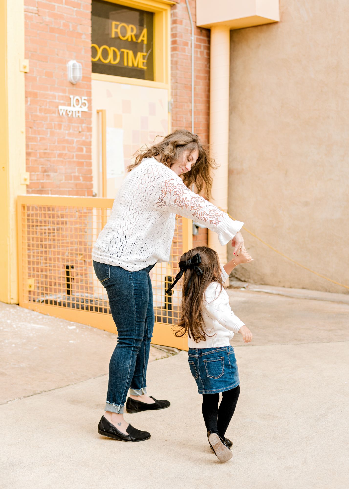 Dancing together in front of brick building with yellow signage.