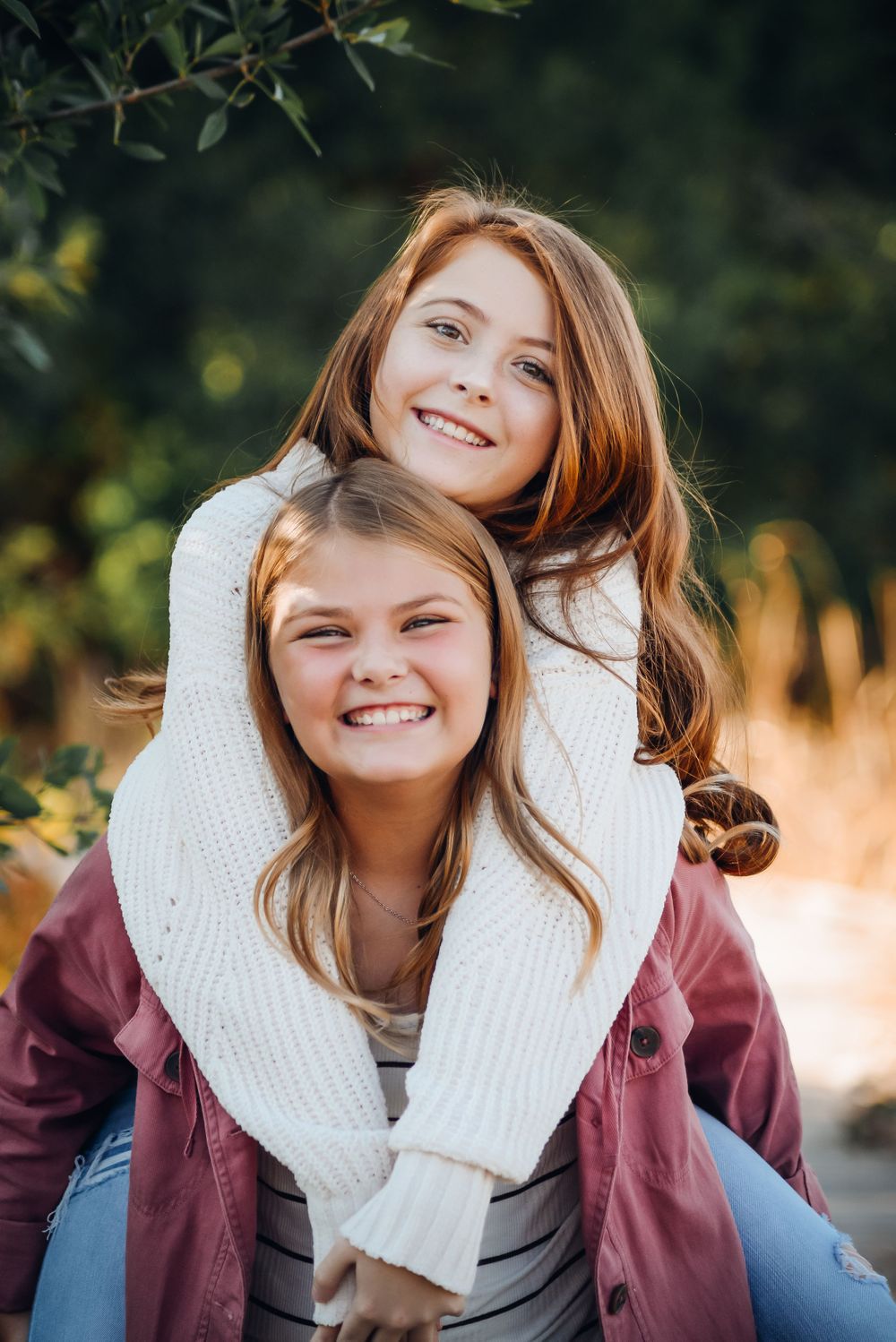 Person in burgundy jacket and white mittens poses playfully during autumn photoshoot.