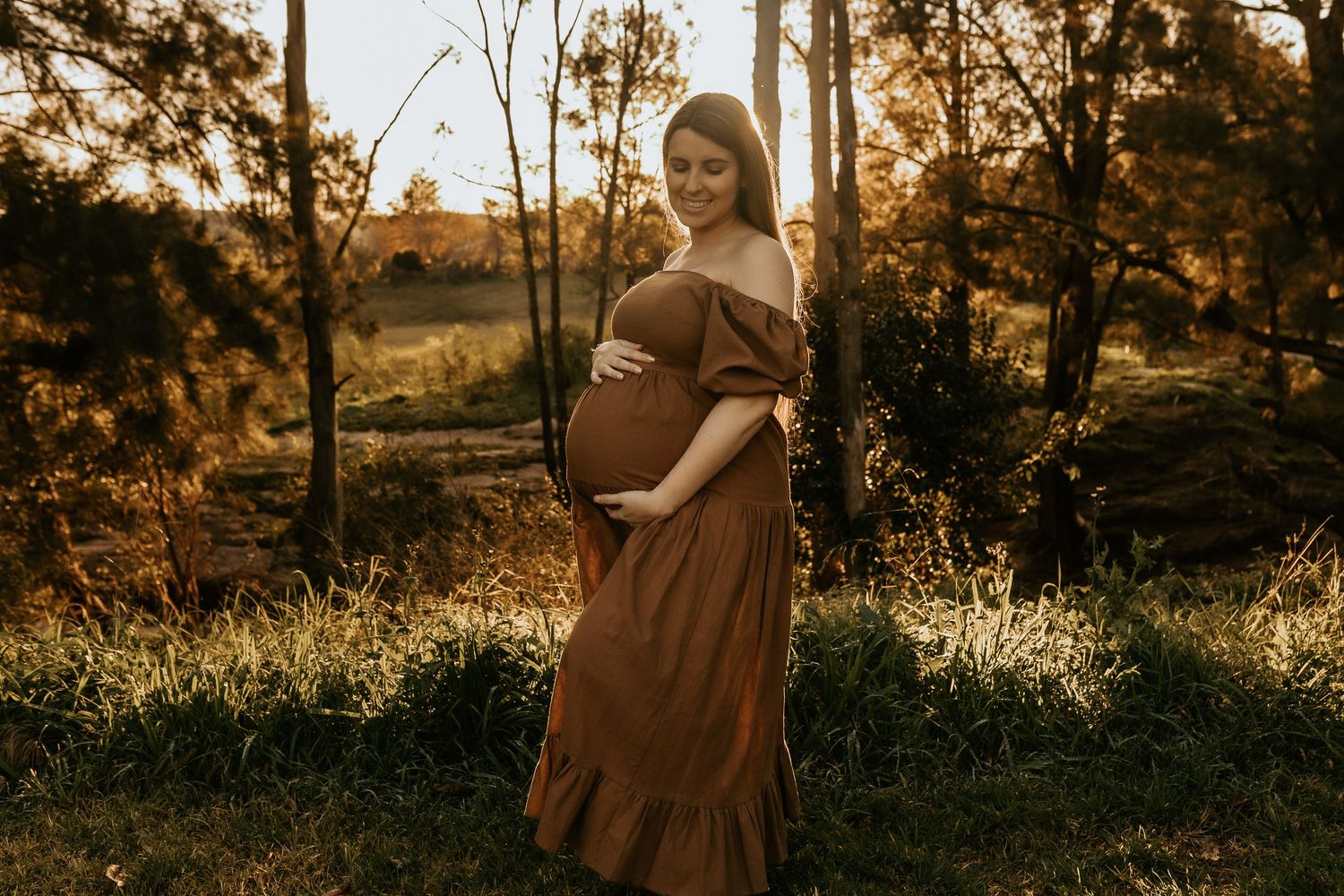 Maternity photography session during golden hour in a natural outdoor setting.
