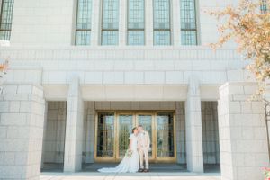 Newlyweds pose together in front of elegant white stone temple doors on their wedding day. Megan Snell Photo Utah Weddings draper temple