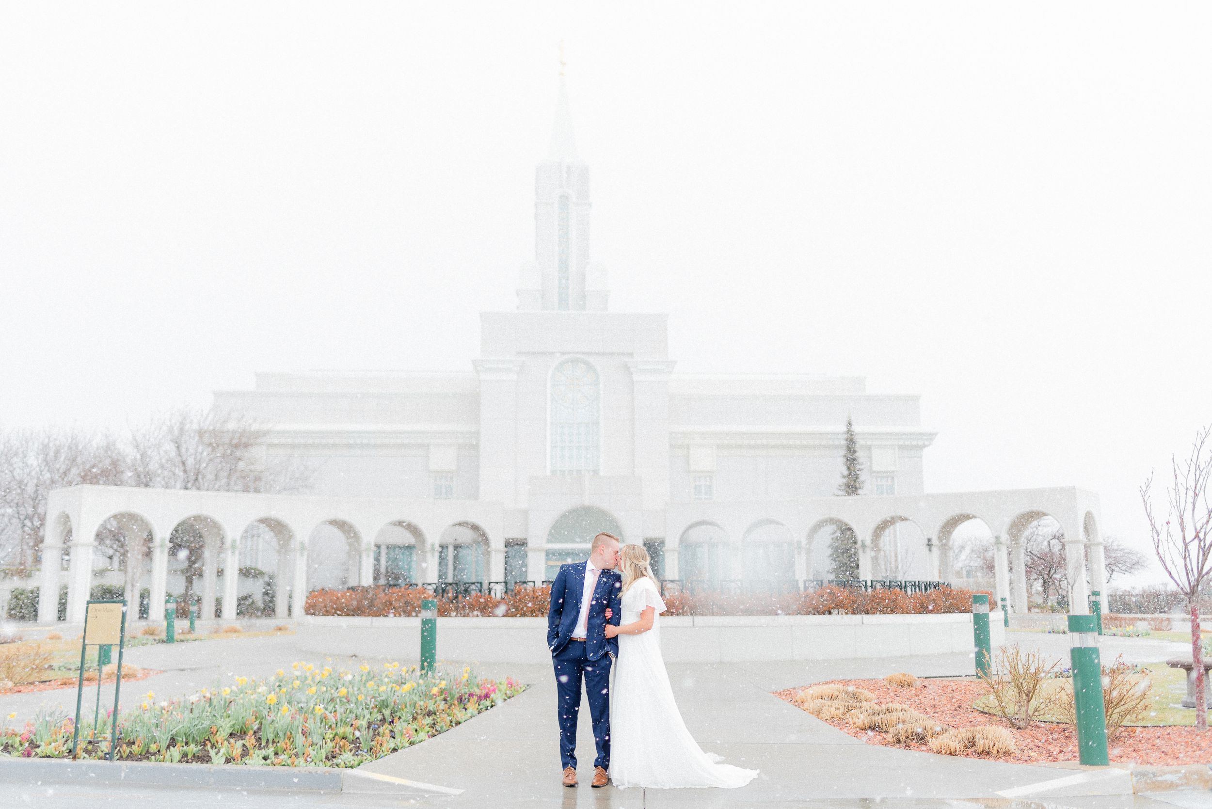 Bride and groom stand together in a misty landscape with a white temple in the background. Megan Snell Photo Utah Weddings