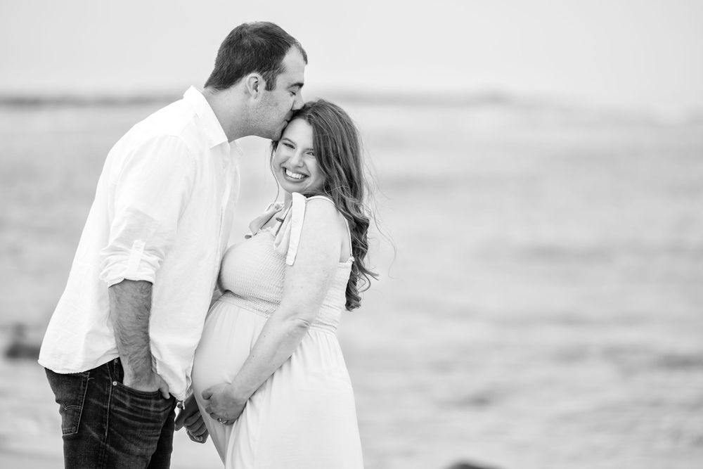 Romantic black and white beach engagement photos with couple in casual attire.