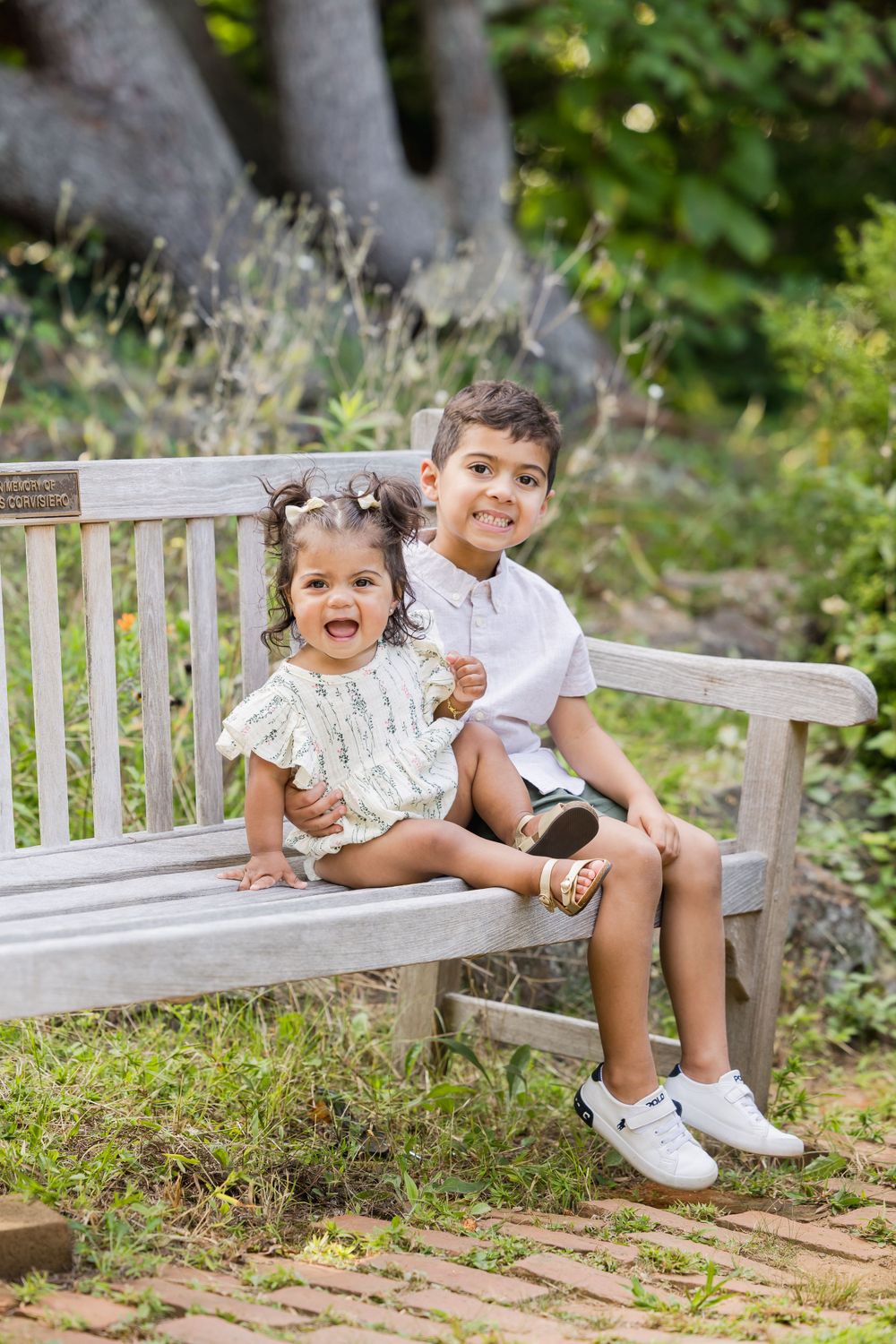 Candid moments of children laughing while sitting on wooden garden bench.