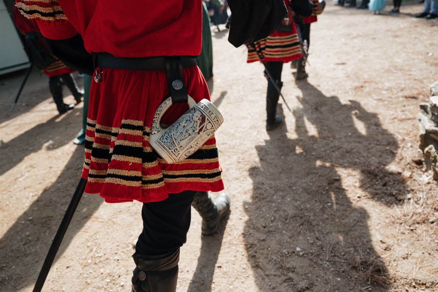 Close-up of red and black striped Renaissance costume details with period-accurate accessories.