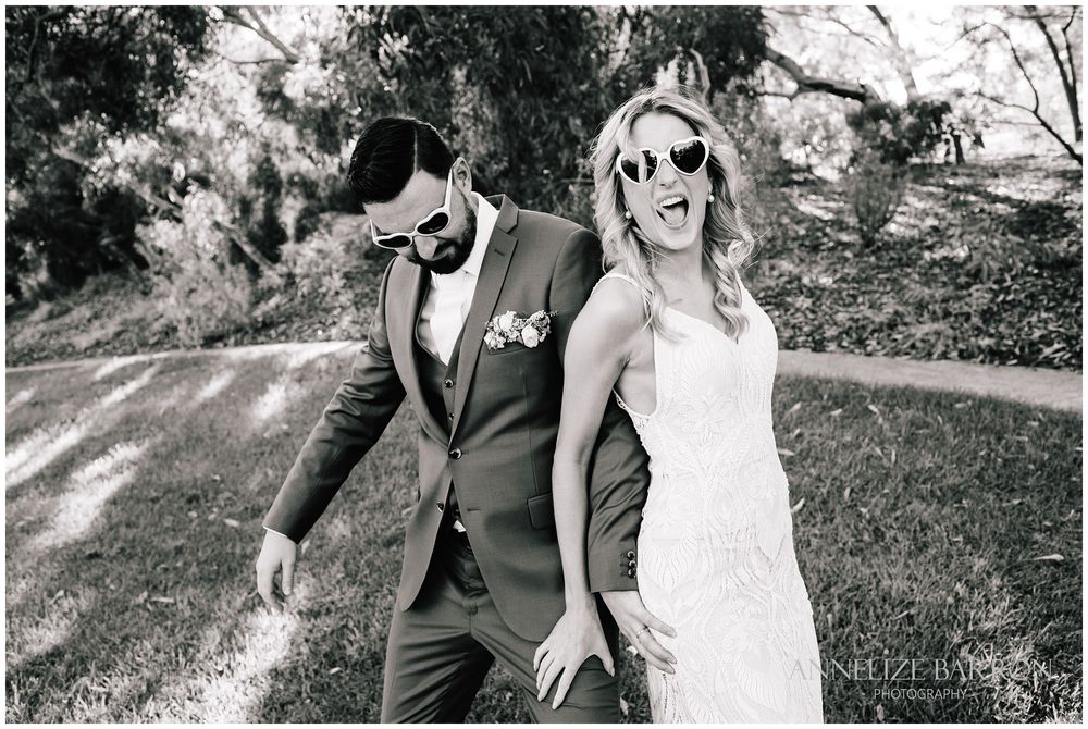 Bride and groom laughing with heart sunglasses on