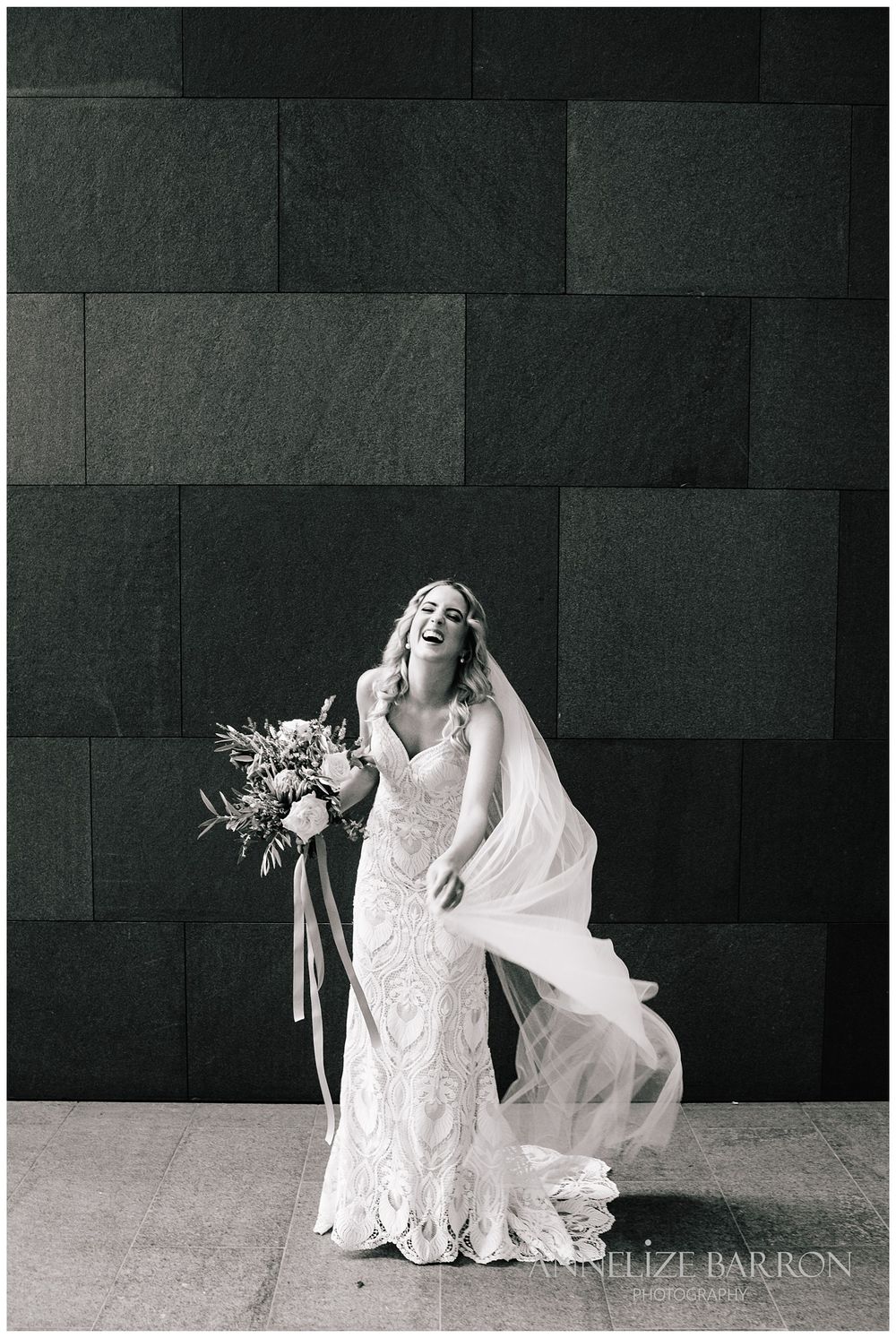 Portrait of the bride laughing as she plays with her veil