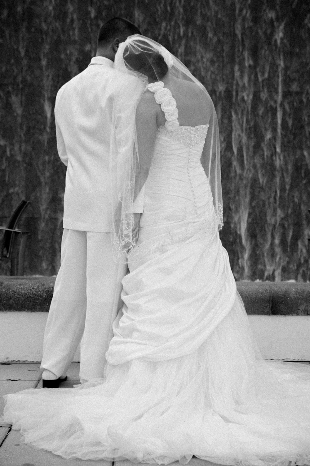 Bride in flowing white wedding dress with long train sitting on marble floor in artistic sequence of poses.