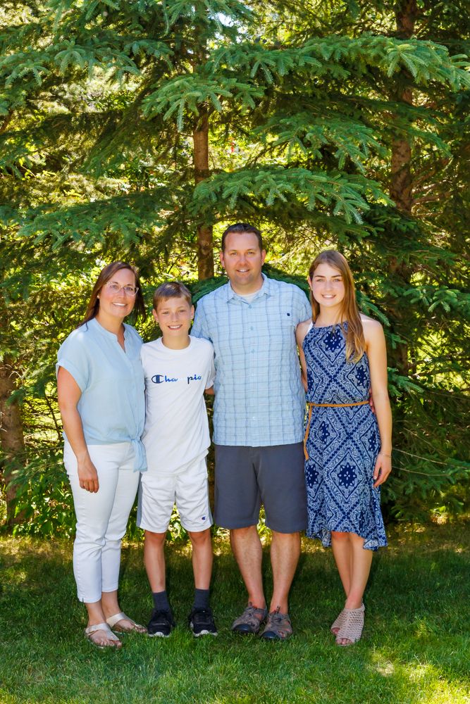 Family photo session with family standing in front of a group of trees.
