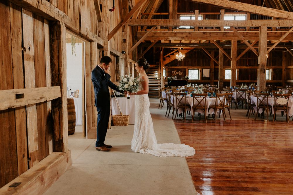 Couple shares first dance in rustic barn wedding venue with wooden beams.