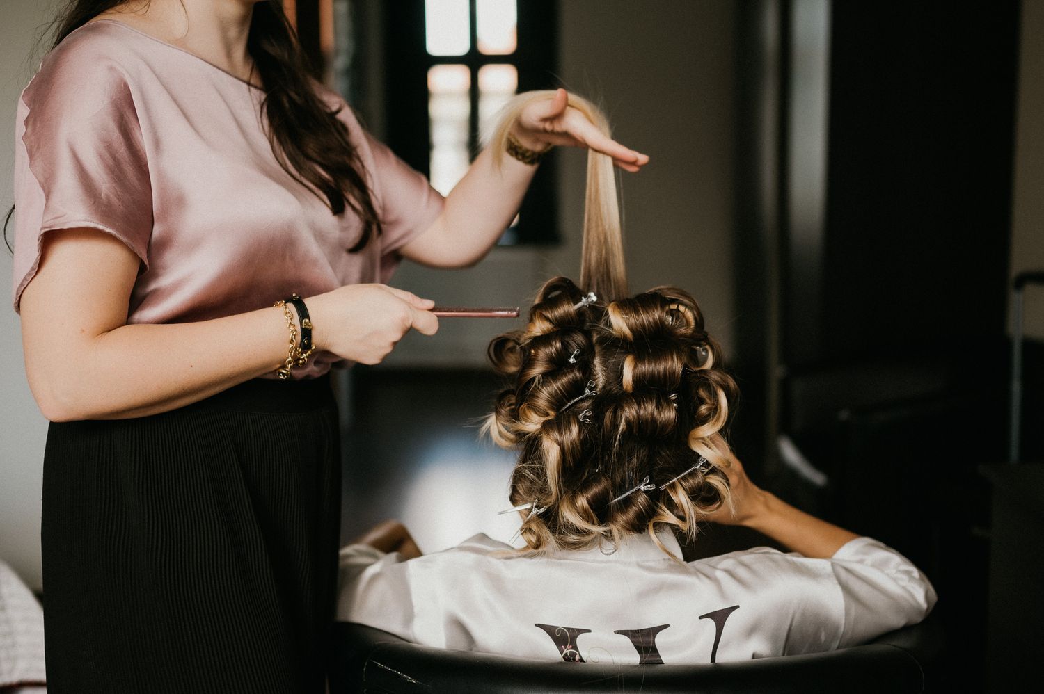 Hairstylist creating elegant curls during a bridal hair preparation session.