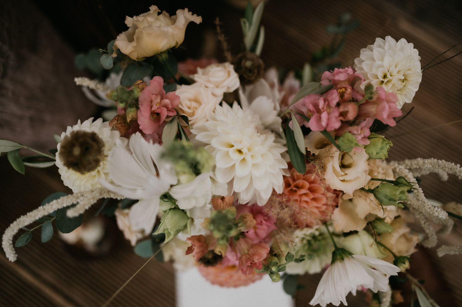 Romantic floral centerpiece with pink and white blooms in soft, moody lighting.