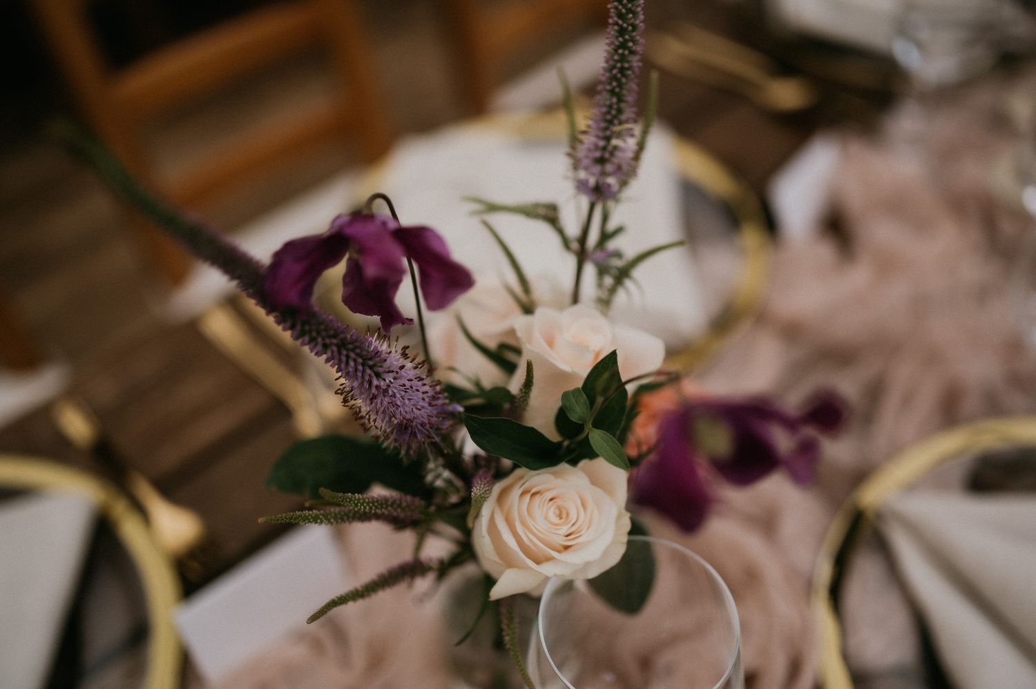 Elegant floral arrangement featuring purple flowers and a white rose with delicate greenery.