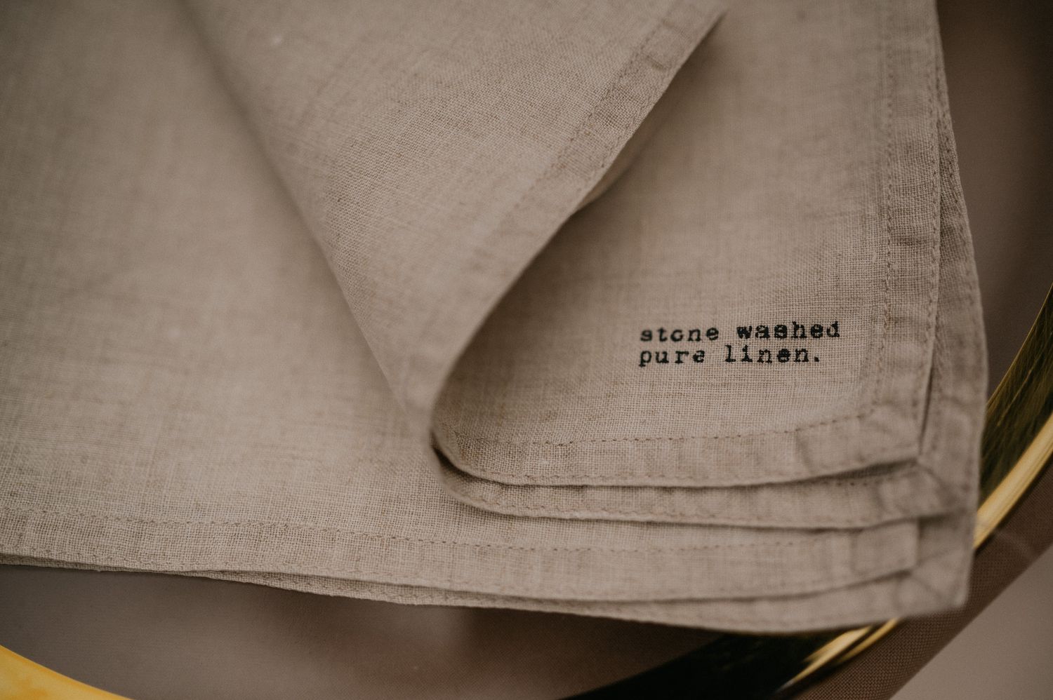 Close-up of gray linen napkin with embroidered text detail.