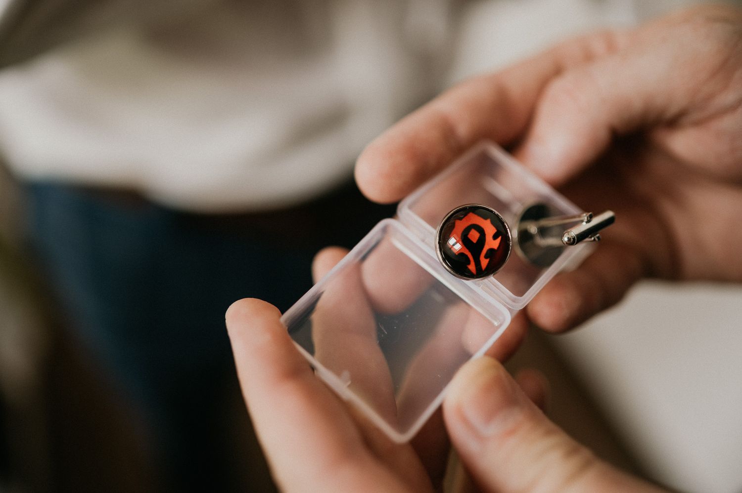 Close-up shot of hands holding a small transparent box with a logo.