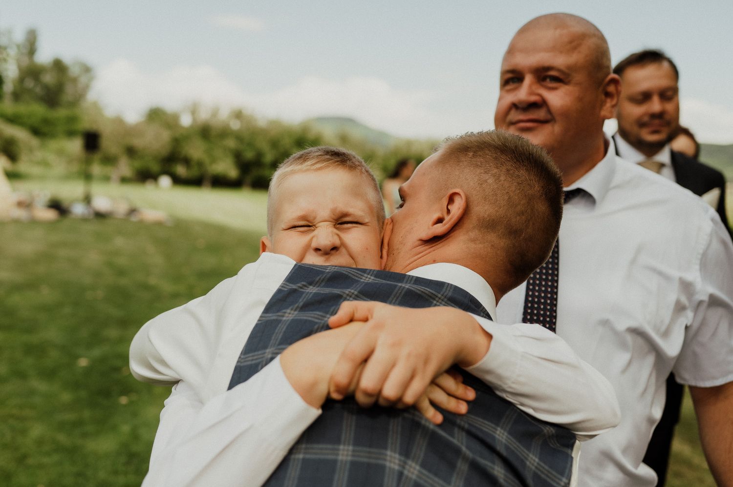 Joyful hugs and embraces shared during outdoor wedding celebration.