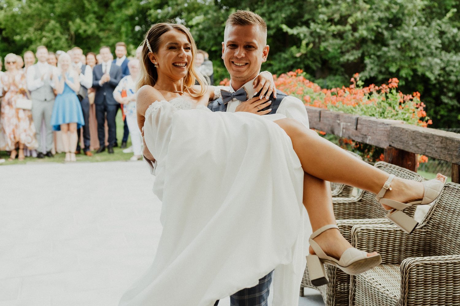 Celebratory lift during wedding festivities with guests watching in background.