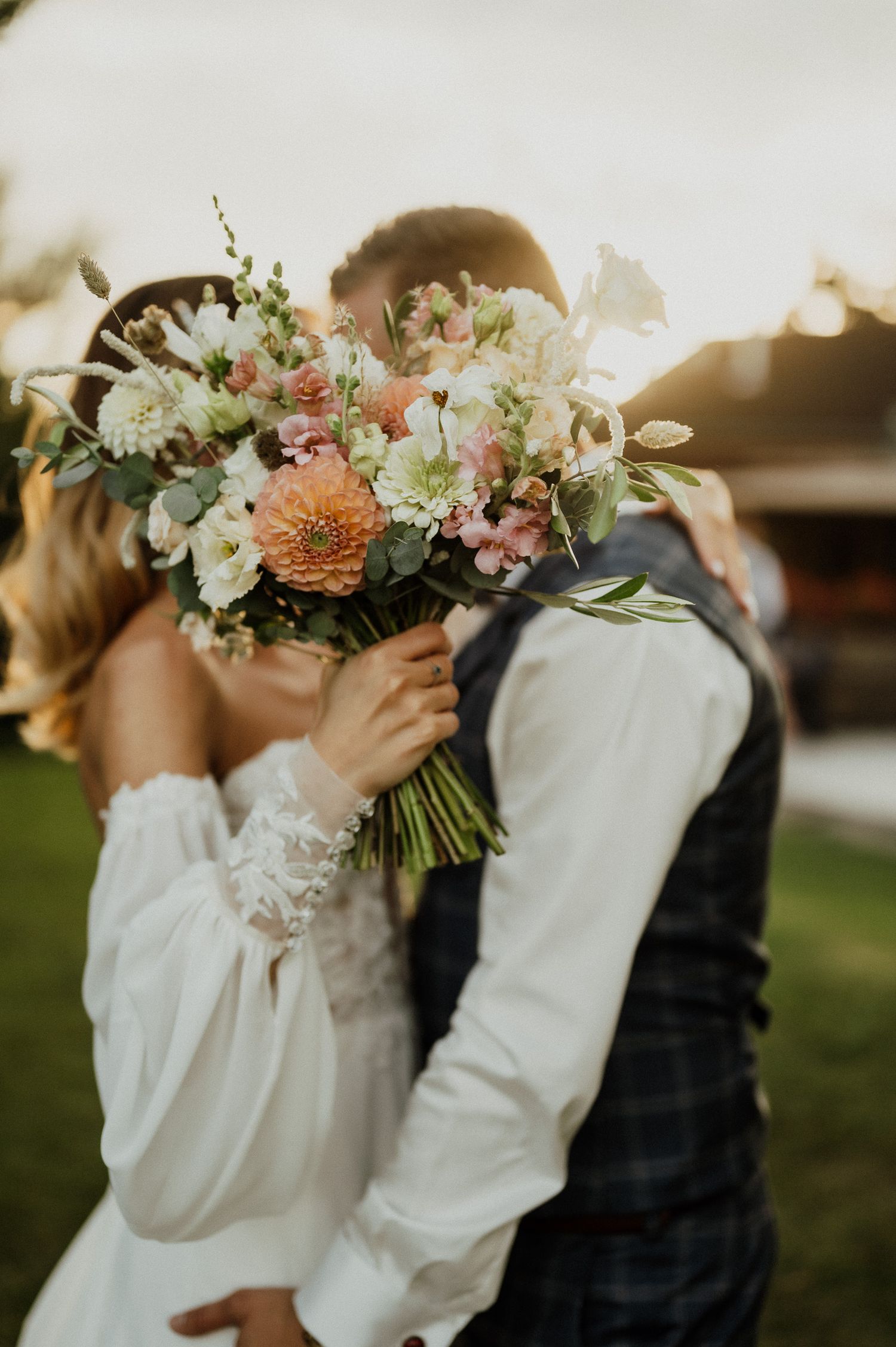 A creative wedding photo with the couple's faces hidden behind a colorful bouquet of flowers.