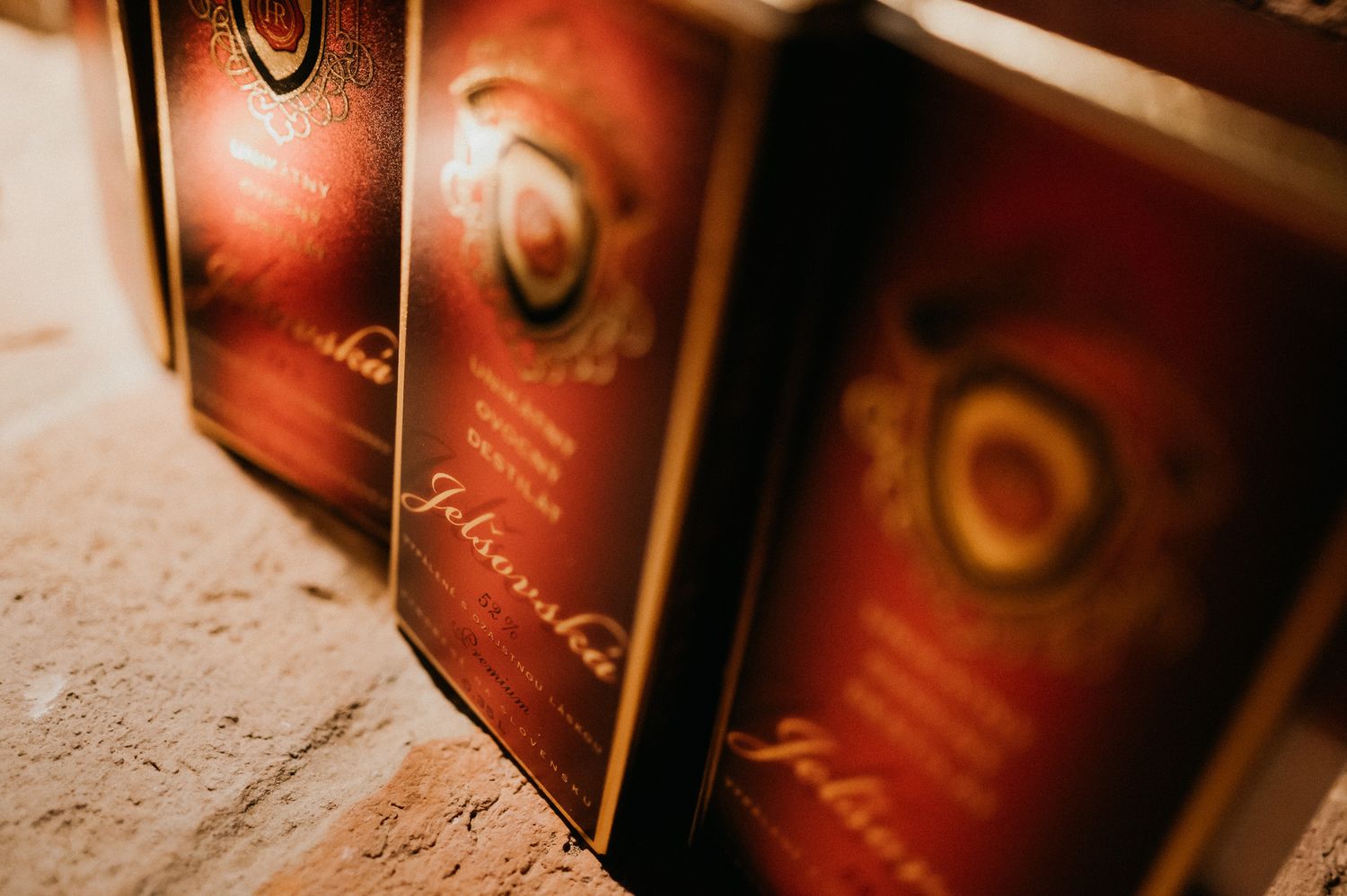 Row of wine bottles with red labels lined up on a textured surface.