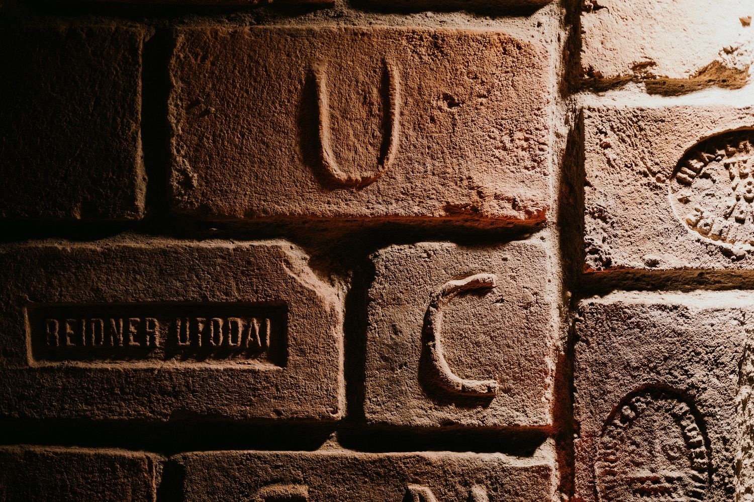 Close-up detail of weathered brick wall with embossed markings.