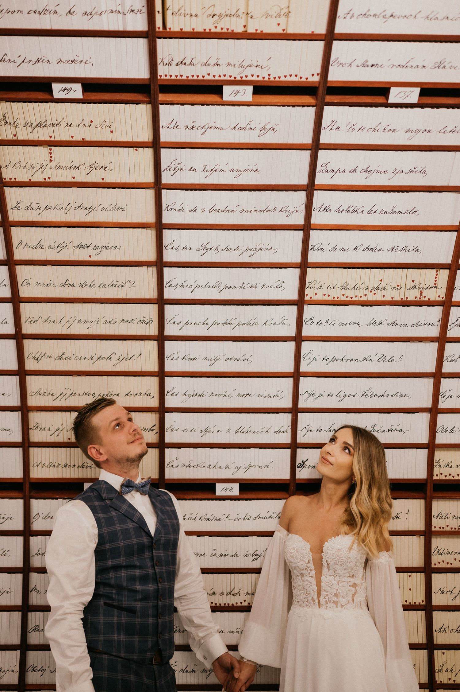 Wedding couple poses against wall of handwritten text in an elegant indoor setting.