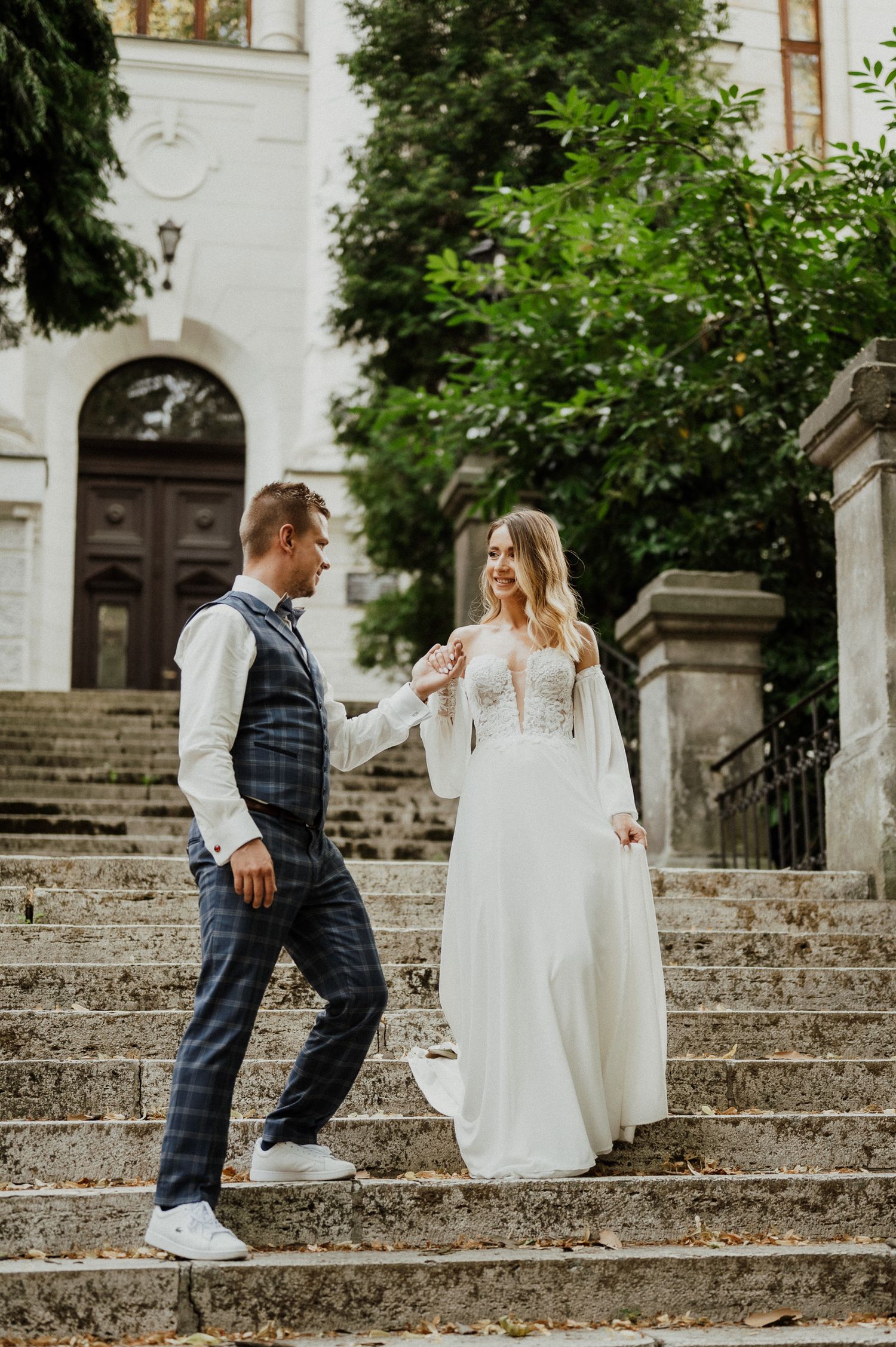 Couple shares playful moment on historic stone steps with classical architecture.