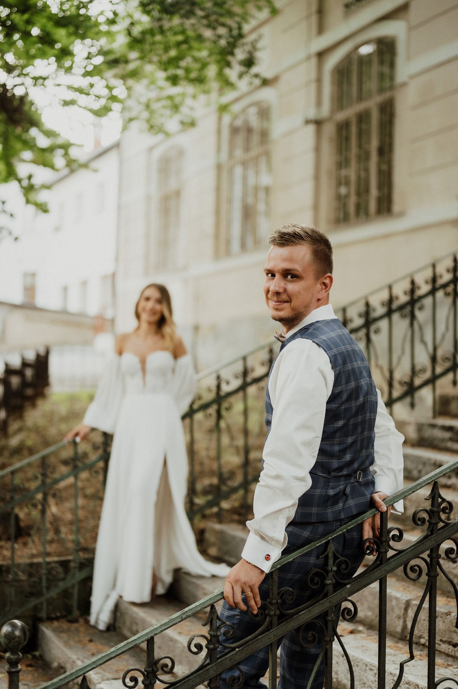 Stylish couple captures candid moment on vintage stone steps with ornate iron railing.
