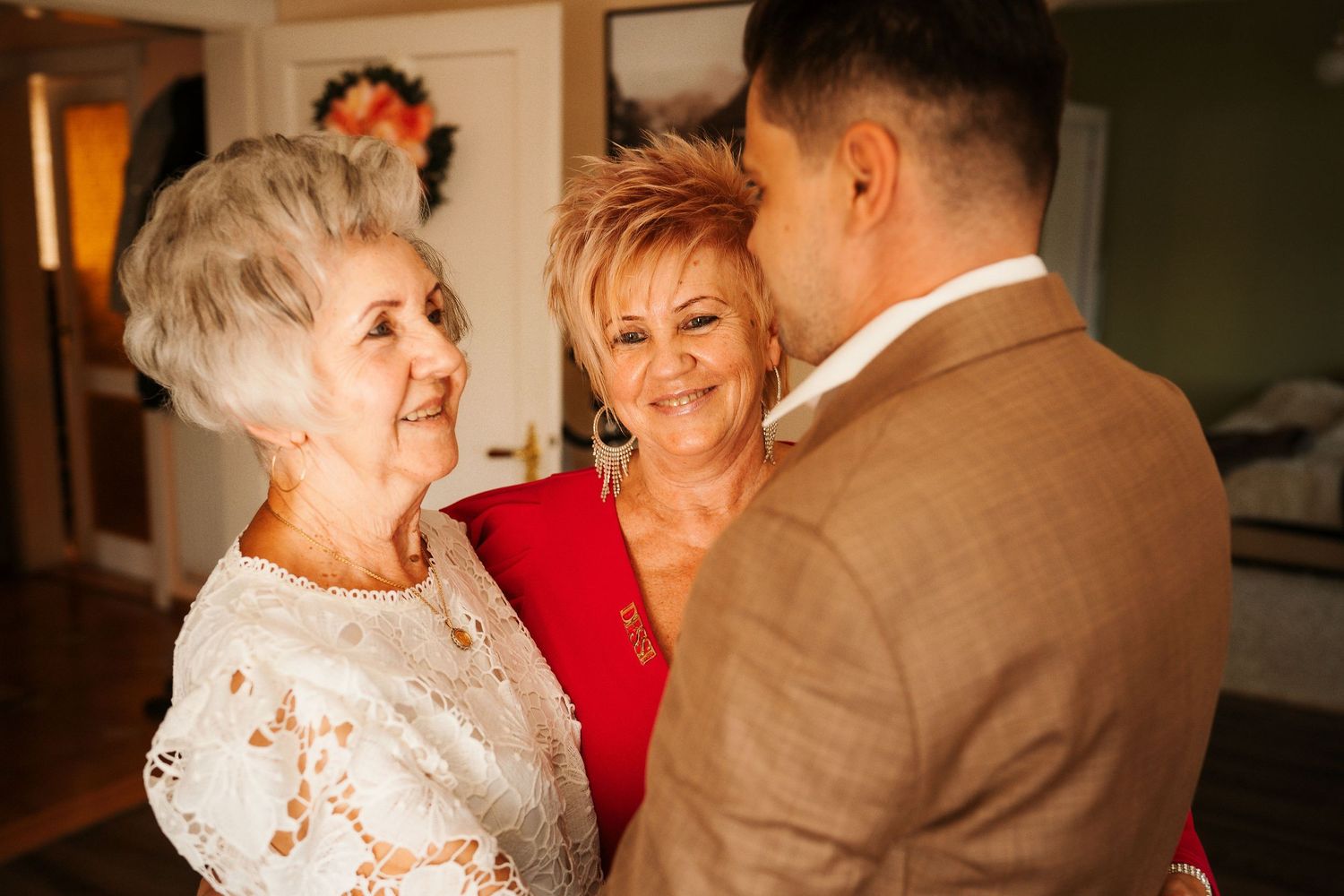 Three people share a meaningful moment during wedding preparations in an indoor setting.