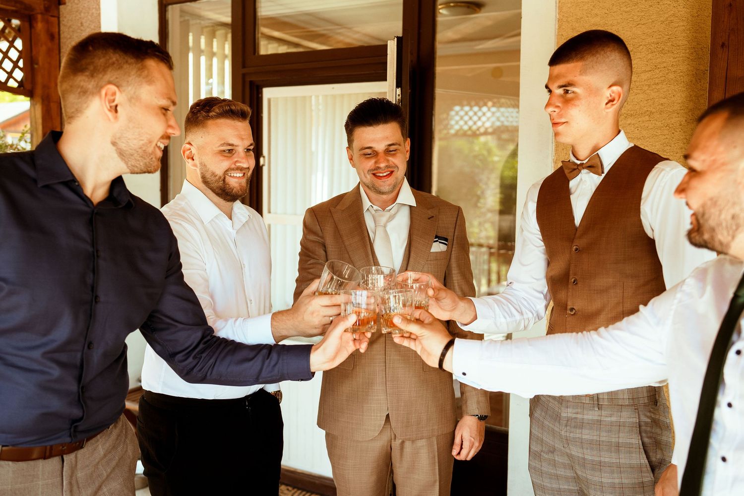 Group of men in formal wear toasting with drinks during a celebration.