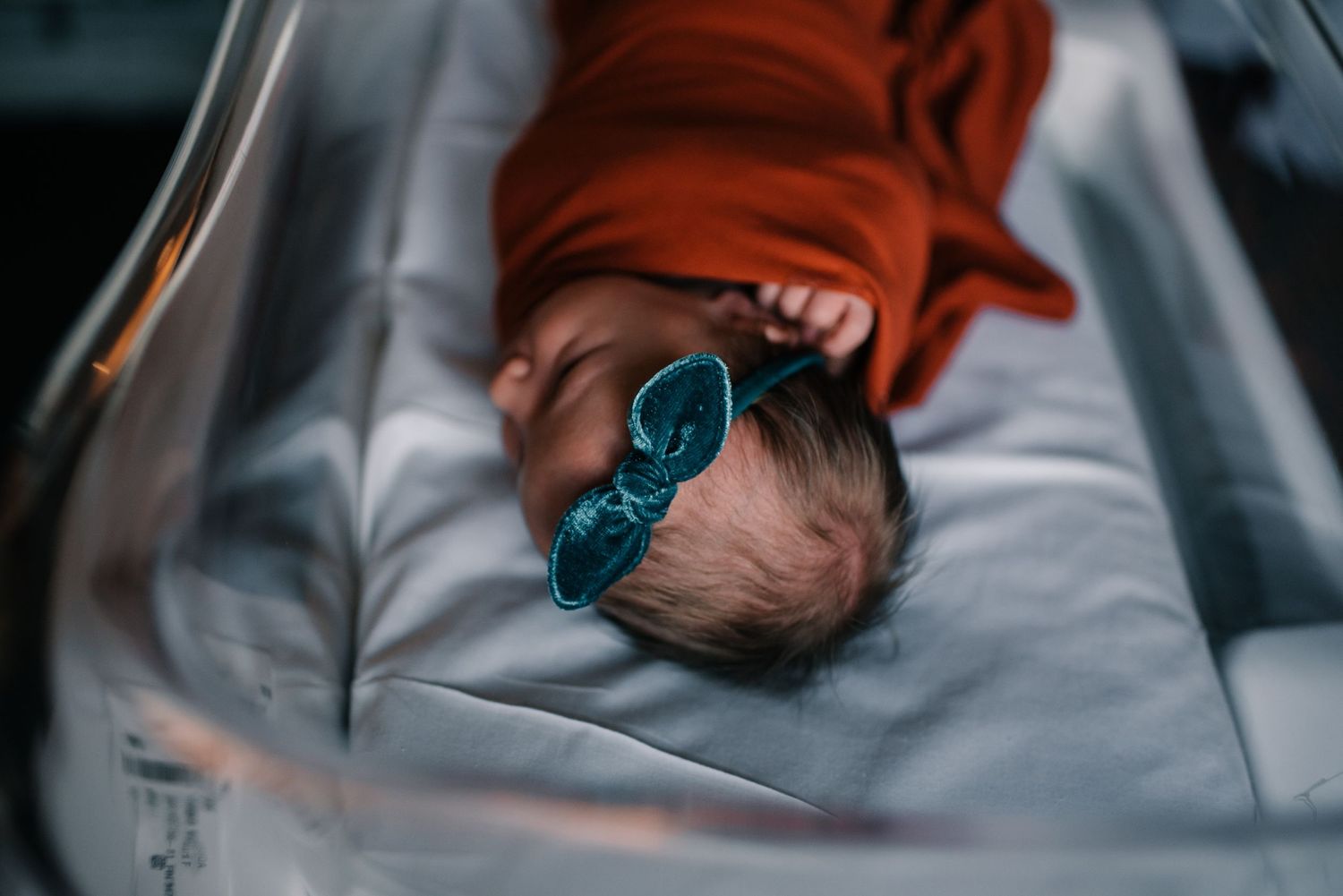 Sleeping infant wearing blue protective eyewear and orange hat.